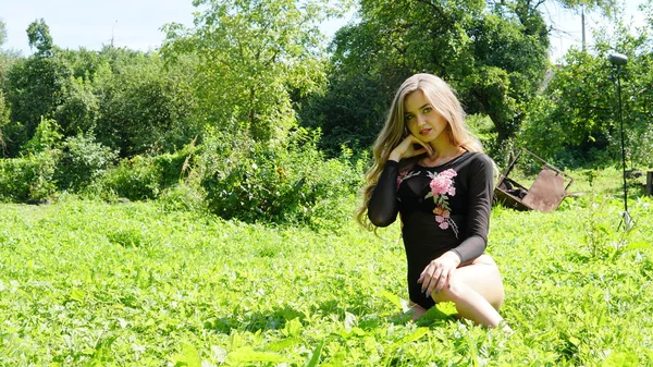 Porträtt av en ung leende blond kvinna som ligger på grönt gräs. — Stockfoto