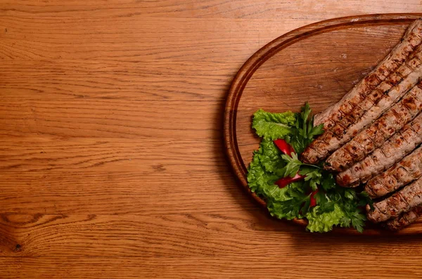 Salsichas grelhadas saborosas em tábua de madeira — Fotografia de Stock