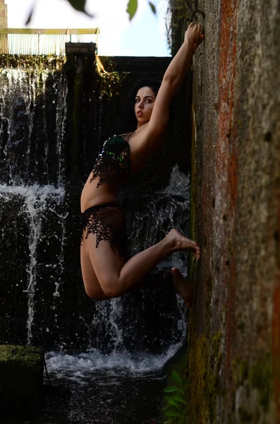 Jonge brunette model poseren tegen een waterval — Stockfoto