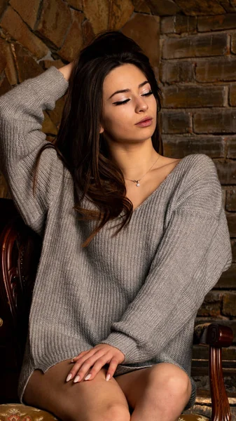 Schöne sexy Mädchen, posiert in einem kurzen grauen Kleid, einem Kamin — Stockfoto