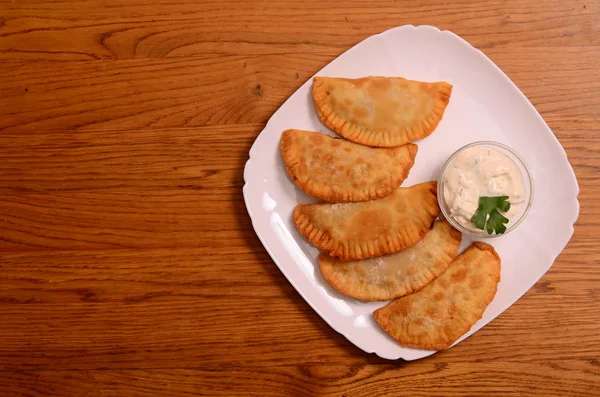 Uzbek eastern Tatar cuisine, cheburek with meat and suluguni cheese in a white plate with vegetables and greens on a wooden table. — Stock Photo, Image