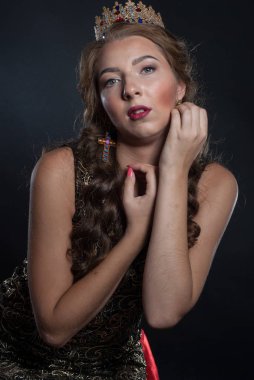 Stüdyoda, kafasında taç olan güzel genç bir kadın poz veriyor.