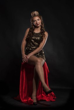 Stüdyoda, kafasında taç olan güzel genç bir kadın poz veriyor.