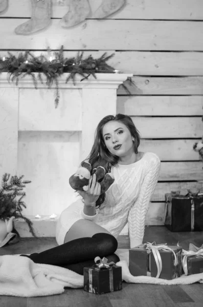 Mulher sexy bonita com árvore de Natal no fundo sentado em cadeira elegante em cenário acolhedor. Retrato de menina posando muito curto vestido branco ajuste apertado. Mulher morena atraente, tiro em casa . — Fotografia de Stock