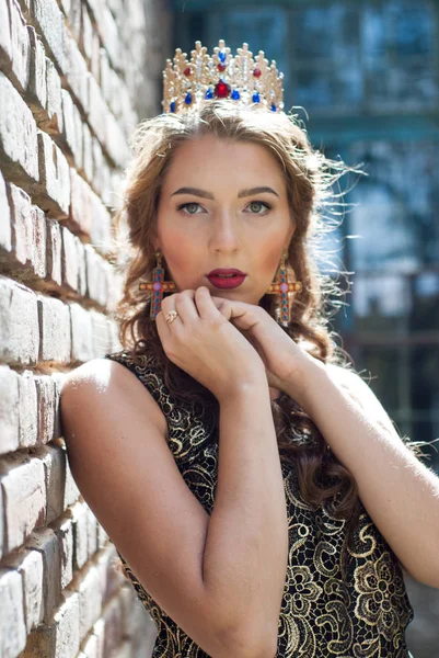 Beautiful young woman in dress with crown on head posing outdoor