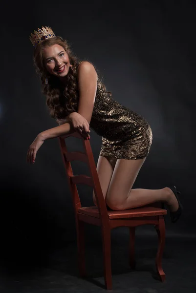 young lovely expression woman in crown posing at studio