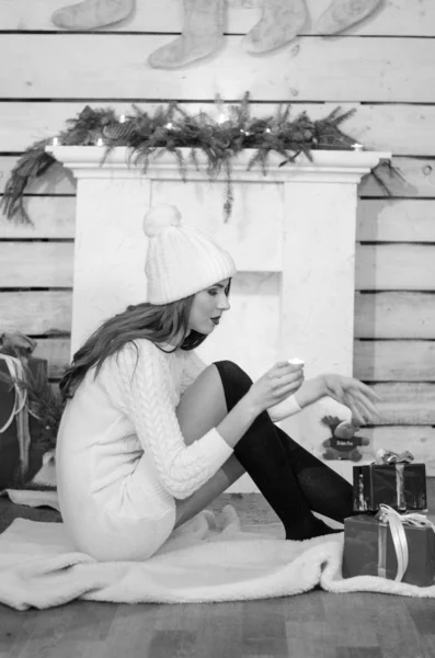 Hermosa mujer sexy con árbol de Navidad en el fondo sentado en una silla elegante en un paisaje acogedor. Retrato de niña posando vestido blanco ajustado bastante corto. Atractiva morena femenina, tiro de interior . — Foto de Stock