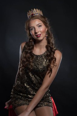 Stüdyoda, kafasında taç olan güzel genç bir kadın poz veriyor.