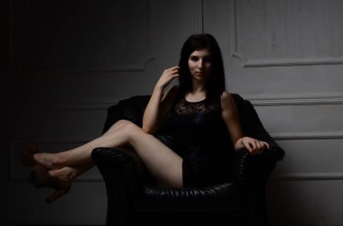 Mini siyah bir elbise giyen, çekici, uzun boylu, gri arka planda esmer, seksi bir kadın.