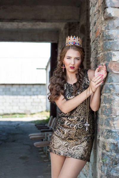 Beautiful young woman in dress with crown on head posing outdoor
