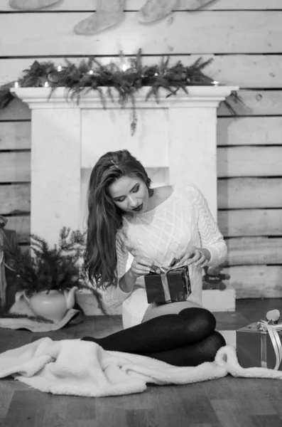 Bella donna sexy con albero di Natale sullo sfondo seduto su una sedia elegante in uno scenario accogliente. Ritratto di ragazza in posa piuttosto corto abito bianco aderente. Attraente bruna femminile, indoor shot . — Foto Stock