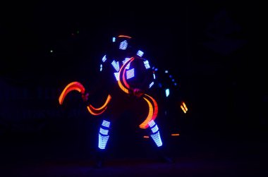 Karanlık sahnede ışıltılı kostümler içindeki sanatçılar   