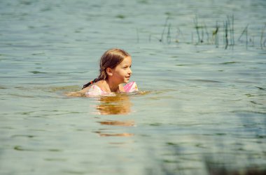 little girl learning how to swim in the lake 