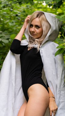 Beyaz pelerinli seksi sarışın kadın doğada