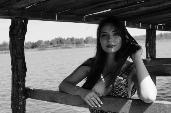 迷人的金发女郎坐在码头旁边的湖与自然背景 浪漫新娘身穿白色连衣裙 捧花花束 — 图库照片