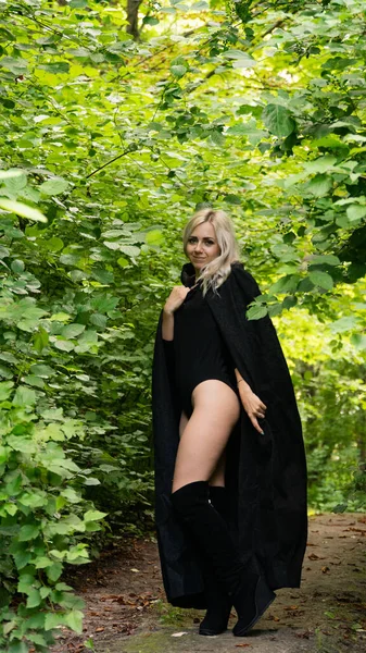 Sexy blonde woman in black cloak nature — Stock Photo, Image