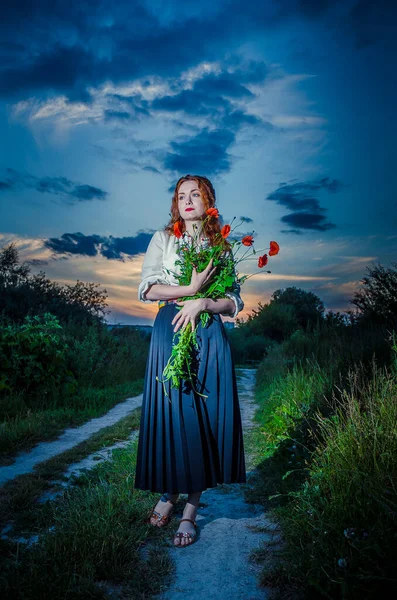 Hermosa chica bronceada en vestido bordado blanco sosteniendo en las manos ramo de espiguillas. Mujer feliz y sonriente divirtiéndose, caminando en el campo. Concepto de estilo de vida rural, tradiciones nacionales . —  Fotos de Stock