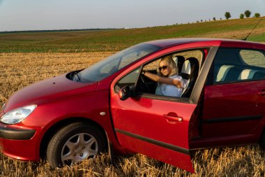 Güzel seksi sarışın kadın, kırmızı araba, tarla