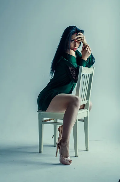 Semi-nude beautiful girl posing on a chair in a classic suit.