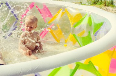Küçük kız şişme yüzme havuzunda suyla oynuyor.