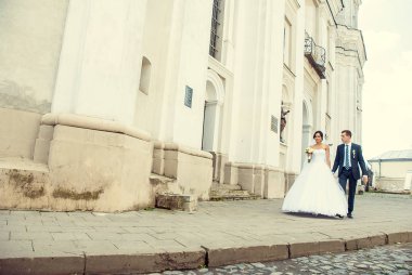 Gelin ve damadın eski binanın önünden geçerken geniş açılı görüntüsü