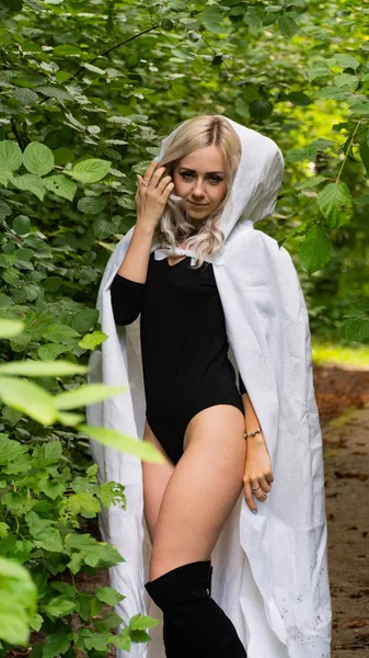 sexy blonde woman in white cloak at nature