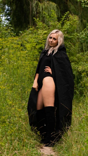 Sexy blonde woman in black cloak nature — Stock Photo, Image