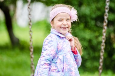 Güneşli yaz parkında oynayan 5 yaşında tatlı bir kız çocuğu. Ormanda yürüyen ve atlayan mutlu bir kız çocuğu. Çocuklar açık havada oynuyorlar..