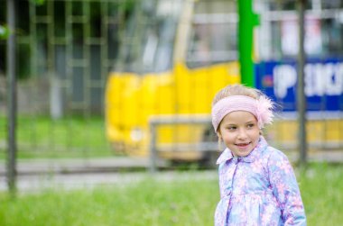 Güneşli yaz parkında oynayan 5 yaşında tatlı bir kız çocuğu. Ormanda yürüyen ve atlayan mutlu bir kız çocuğu. Çocuklar açık havada oynuyorlar..