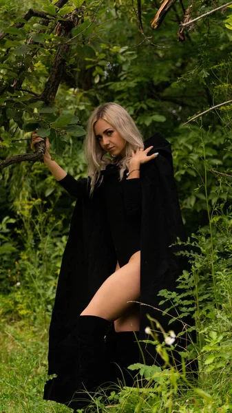 Sexy blonde woman in black cloak nature — Stock Photo, Image