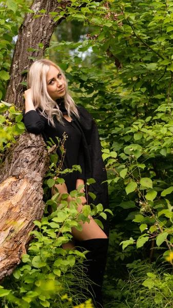 Sexy blonde vrouw in zwart mantel natuur — Stockfoto