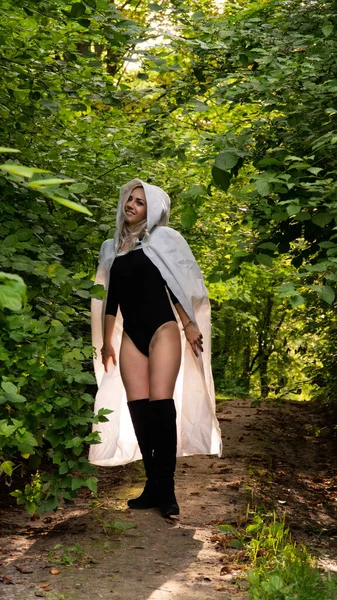 sexy blonde woman in white cloak at nature