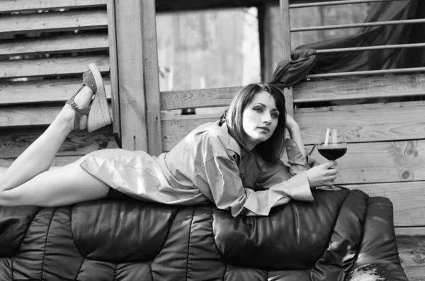 Jeune femme se détendre et boire un verre de vin rouge sur le balcon au coucher du soleil le soir . — Photo