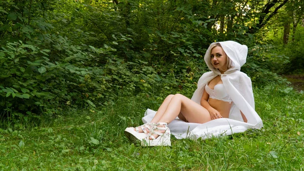 Hermosa mujer rubia sexy, la imagen de una monja en un impermeable blanco — Foto de Stock