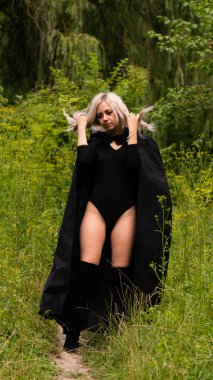 Siyah pelerinli seksi sarışın kadın.