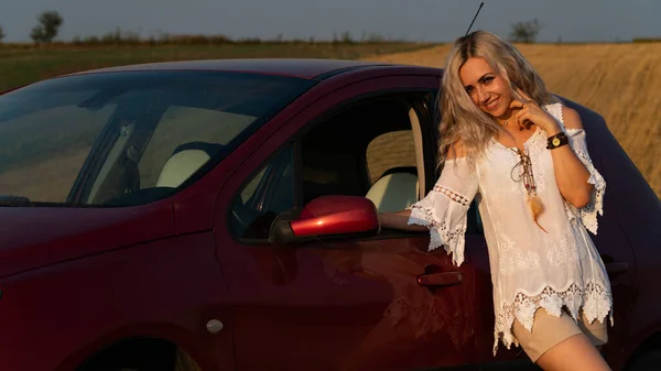 Schöne sexy blonde Frau, rotes Auto, Feld — Stockfoto