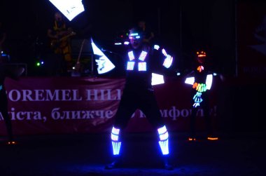 Karanlık sahnede ışıltılı kostümler içindeki sanatçılar   