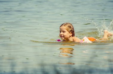little girl learning how to swim in the lake 