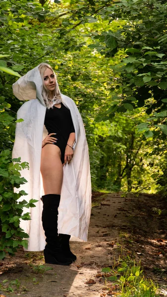 sexy blonde woman in white cloak at nature