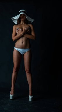 Genç, güzel, esmer, çıplak, mükemmel vücutlu, seksi iç çamaşırlı, siyah arka planda poz veren kadın..