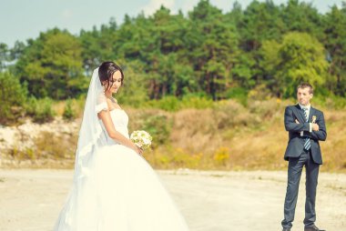 Yeni evliler doğal ortamda poz veriyorlar. Arka planda orman var.