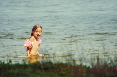 little girl learning how to swim in the lake 