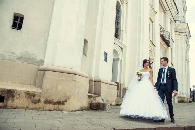 Gelin ve damadın eski binanın önünden geçerken geniş açılı görüntüsü