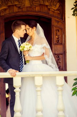 Damat ve gelin balkonda birlikte poz veriyorlar.