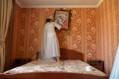 Beyaz elbiseli gelin düğünden önce odada poz veriyor.