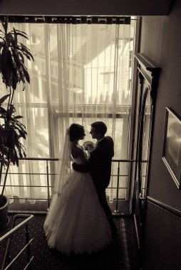 Yeni evli çift oteldeki merdivenlerde nazikçe poz veriyor.