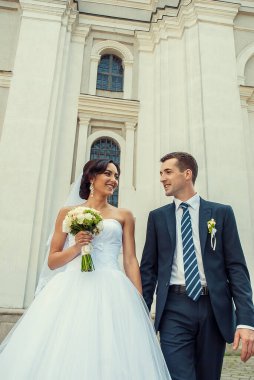 Mutlu gelin ve buket ve damat eski binanın önünden geçiyor.