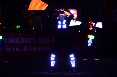 Karanlık sahnede ışıltılı kostümler içindeki sanatçılar   