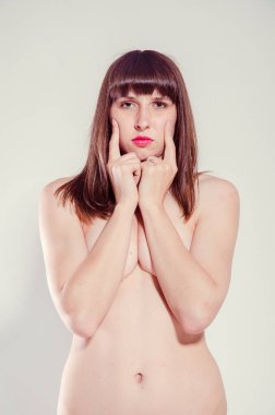 Külotlu çıplak bir kadın stüdyo arka planında poz veriyor. 