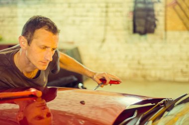 Kırık anahtarla araba tamir eden tamirci.